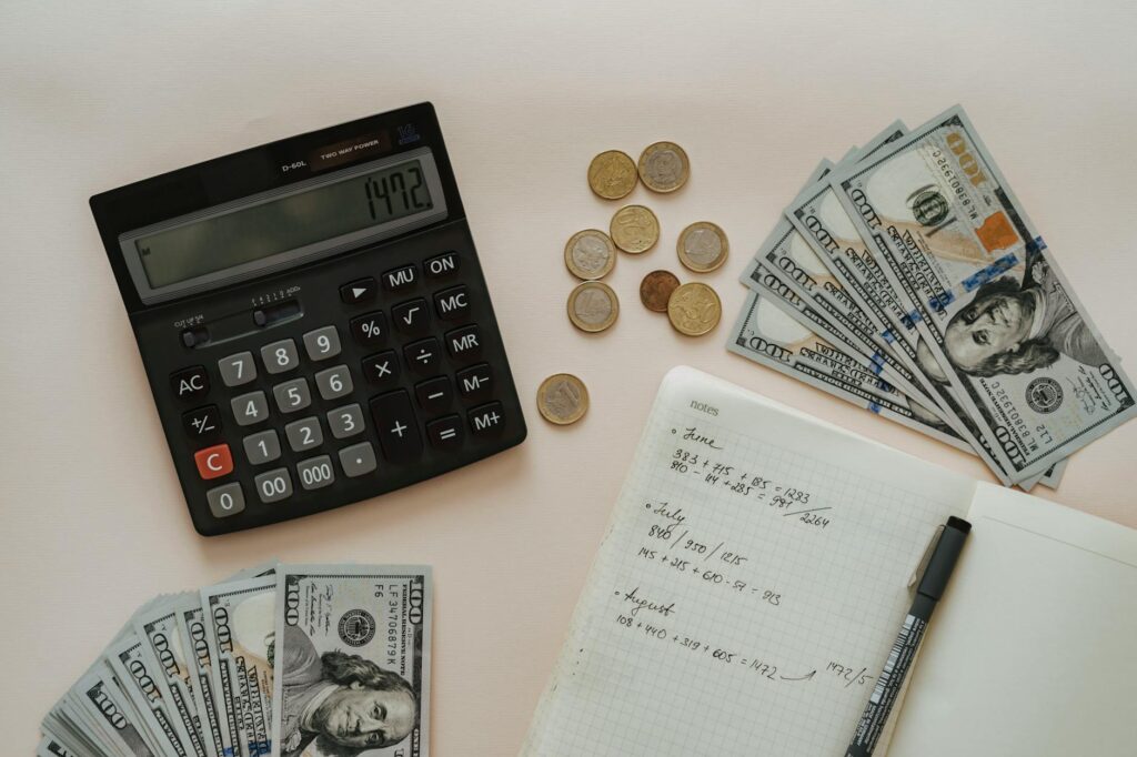 black calculator beside coins and notebook